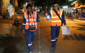 Công nhân vừa di chuyển, vừa đeo thiết bị dò tìm đường ống nước bể.